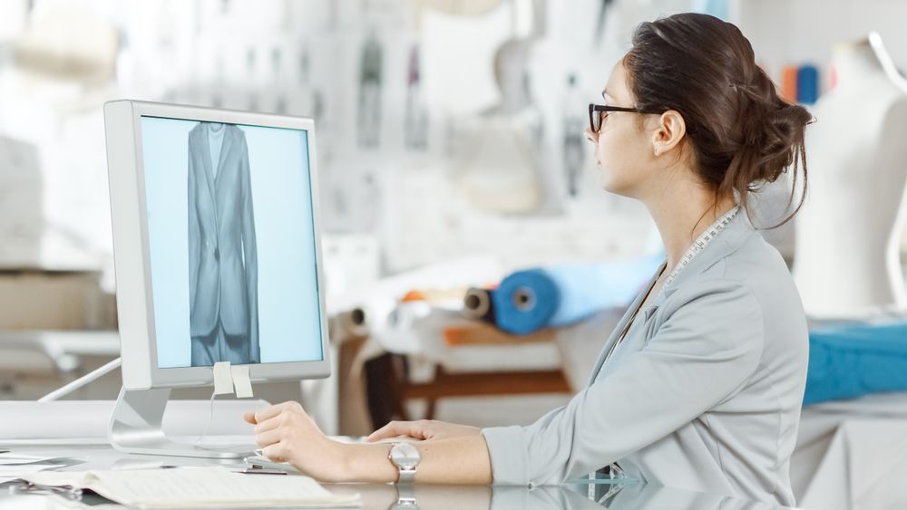 fashion, designer,  Sits at Her Desk Working on Sketches on Her Personal Computer. Her Studio is Sunny,