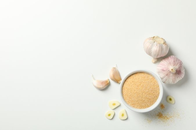 Top view of bowl of garlic powder with bulbs with copy space