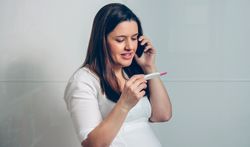 Pregnant talking on mobile looking pregnancy test