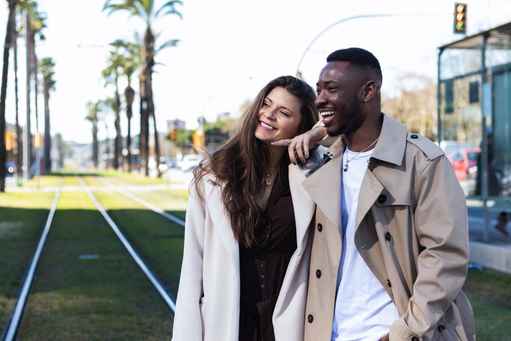 Happy multiethnic couple in stylish clothes walking around the city