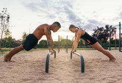 couple doing push ups on a bar in a calisthenic park