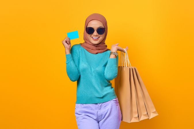 Muslim woman smiling with shopping bags and credit card