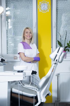 Female dentist in purple gloves in bright modern office