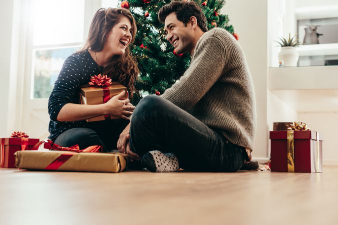Happy couple exchanging Christmas presents in their living room