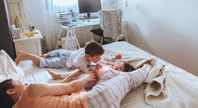 Portrait of happy young family playing in bed on a relaxed morning