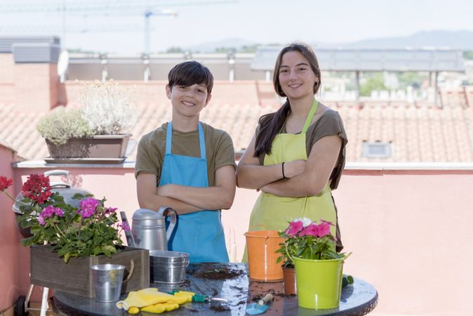Two happy teenagers wearing gardener aprons posing on home terrace