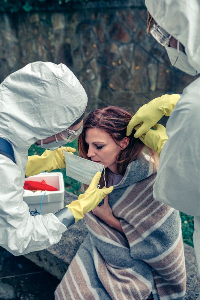 Doctors putting protective mask on woman infected with a virus