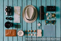 Mix of travel items; hat, camera, map, compass, seashells, arranged on blue background 5rkOp4
