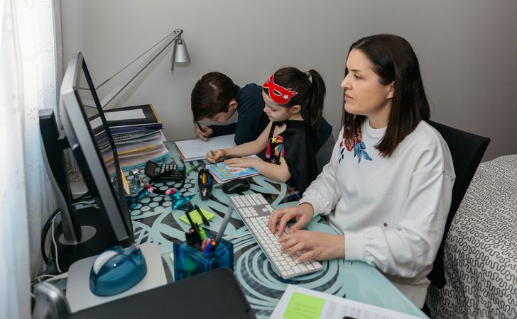 Woman teleworking with her children doing homework