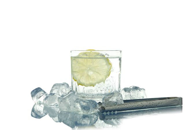 Rocks glass full of ice with lemon slice, next to tongs