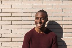Happy young Black male standing near billet wall