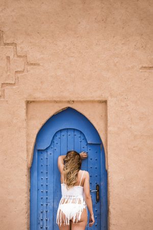 Anonymous woman leaning on blue door
