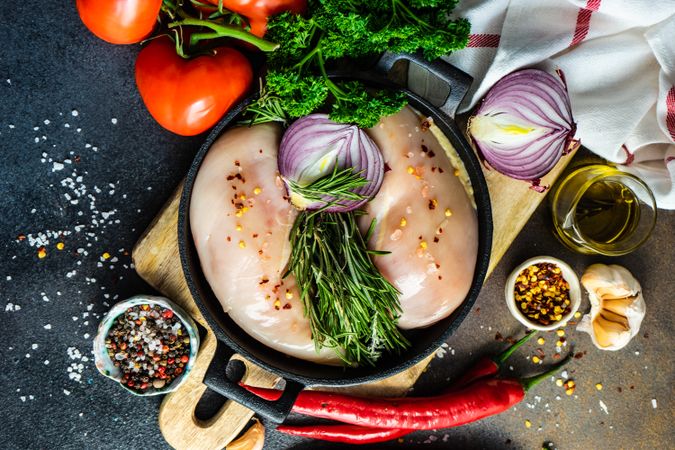 Top view of vegetables & chicken breasts ready for dinner prep on cutting board