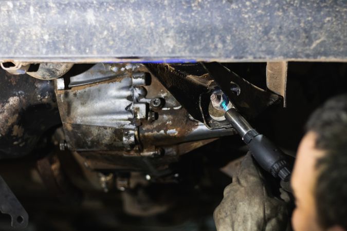 Anonymous repairman removing car details with torch during work in auto service