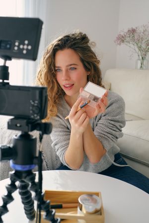 Female beauty blogger recording video on camera at home