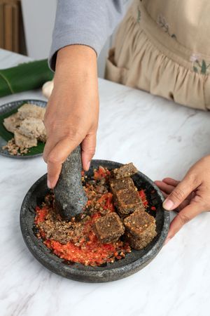 Female hand Crushed Roasted Oncom on the Chilli, Step making Sambal Oncom