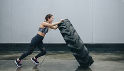 Sportswoman doing cross-training lifting a tire