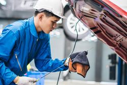 Repairman checking oil of car engine