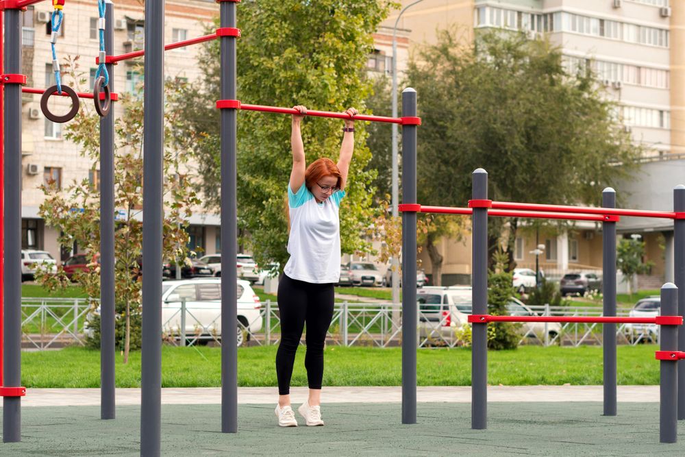 Woman hanging from horizontal bar at outdoor