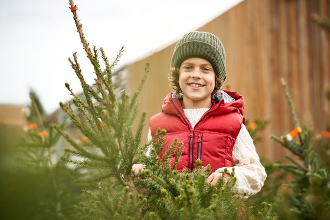 Smiling boy standing near New Year spruce