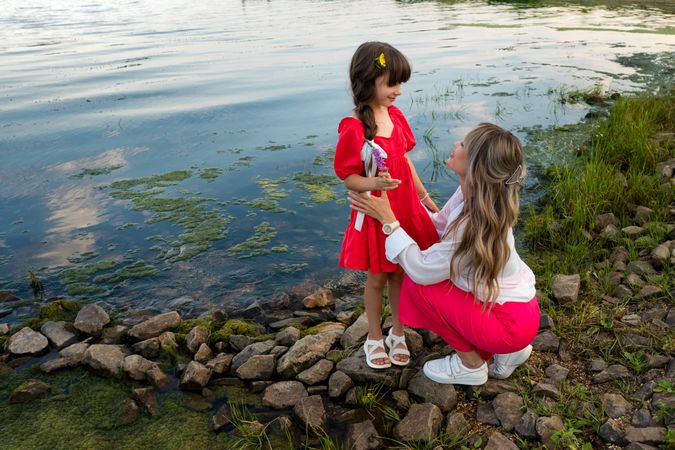 Mom and little daughter walking by the lake or pond