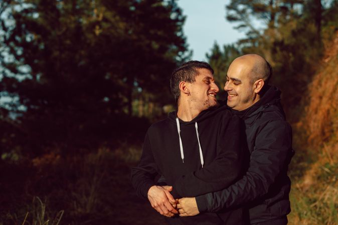Smiling men hugging on path in park