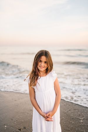 Smiling girl standing on seaside among waves