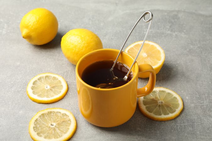 Cup of tea and lemons on grey background, closeup