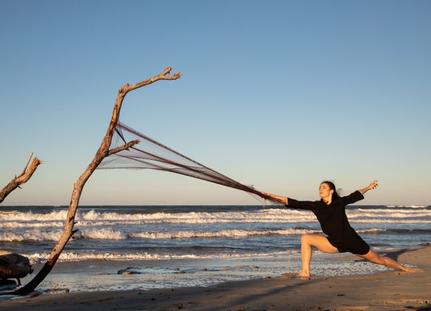 Woman in fishing net fixed on twig near water on shore