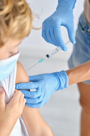 Crop nurse with syringe vaccinating patient in hospital