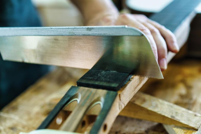 Man scoring fretboard of guitar on workbench in luthier workshop