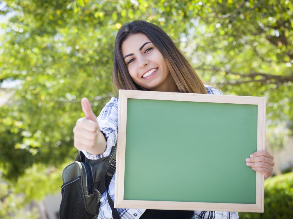 Excited Female Student Holding Blank Chalkboard With Thumbs Up