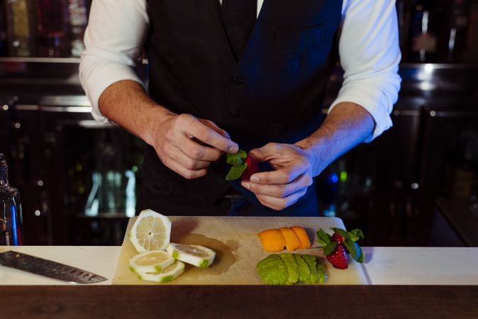 Barman working preparing fruits for cocktail drinks