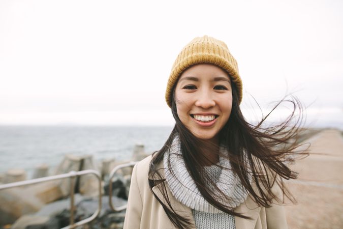 Young Asian woman smiling in yellow beanie