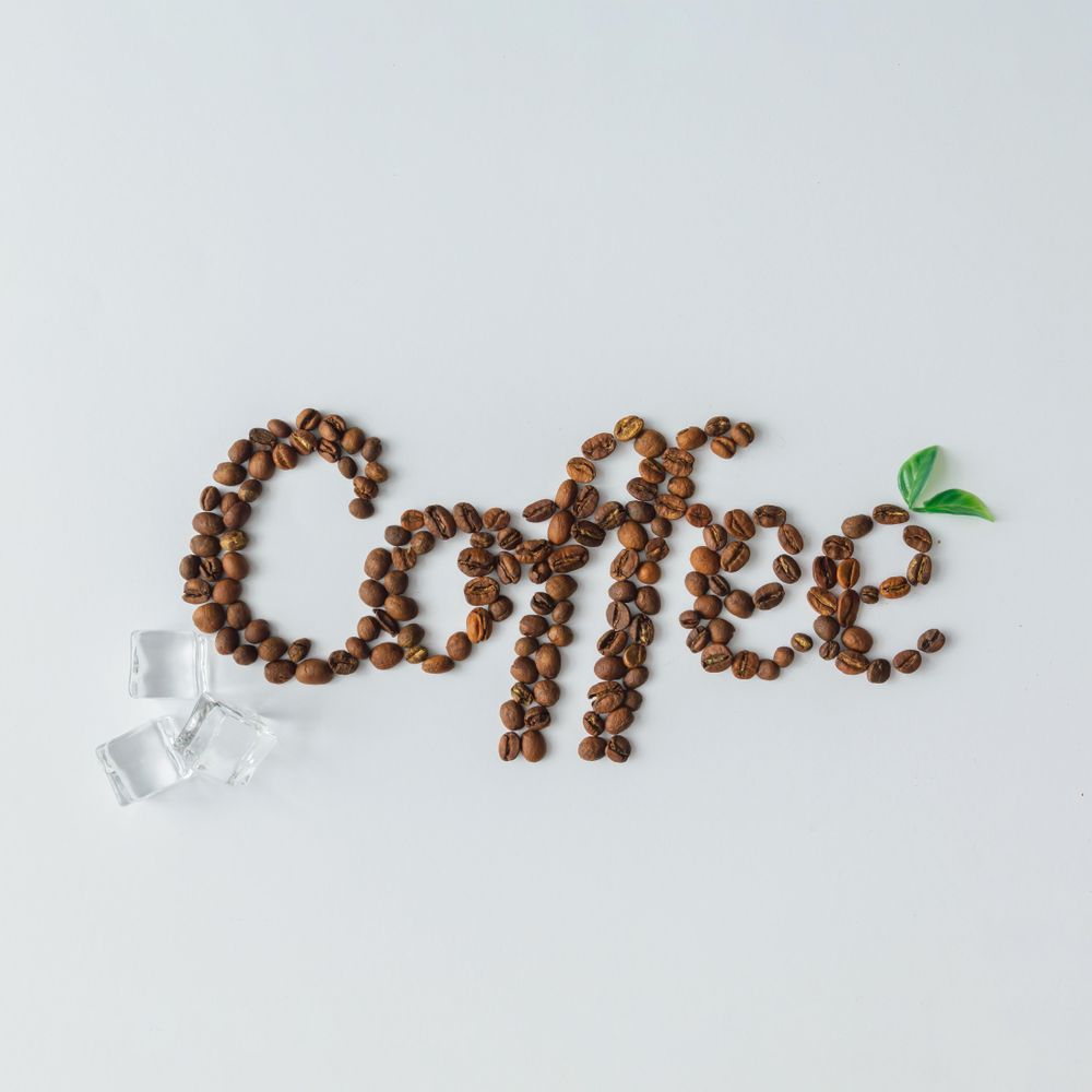 Coffee beans spelling out “Coffee” with ice cubes on bright background