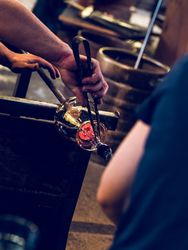Anonymous masters making glass utensil in factory