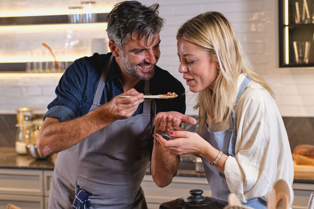 Husband feeding wife while cooking