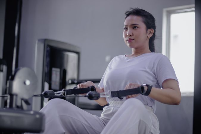 Focused woman using rowing machine for strength training session