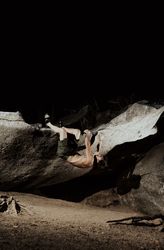 Man practicing rock climbing among large rocks in a forest