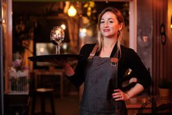 Cheerful waitress holding tray with wineglasses