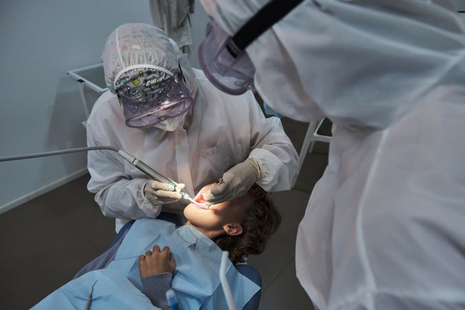 Dentist treating teeth of boy in dental office