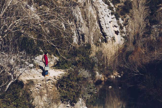 Traveling woman on lake in rocky cliffs