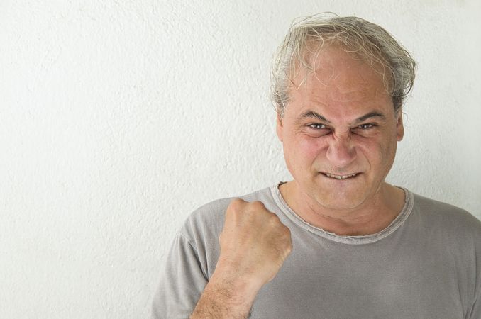 Portrait of excited middle aged man in gray shirt against light background