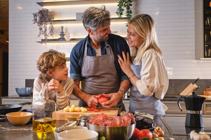 Man peeling tomatoes while cooking with wife and son