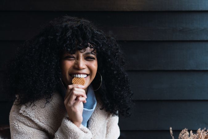 Cheerful Black woman eating cookie