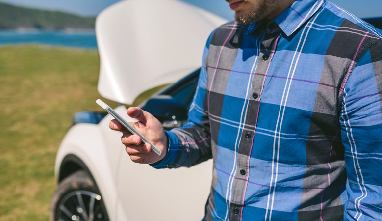 Young man with broken down car calling by mobile