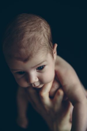 Newborn baby girl held by one hand
