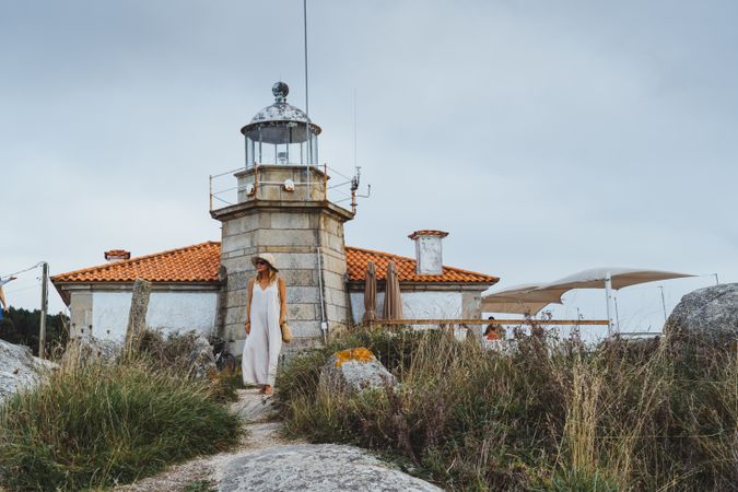 Woman in hat standing against beacon on seashore