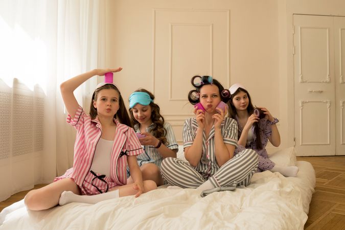 Girls and mom laugh and enjoy a pajama party.