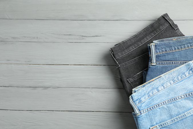 Different jeans on grey wooden background, space for text